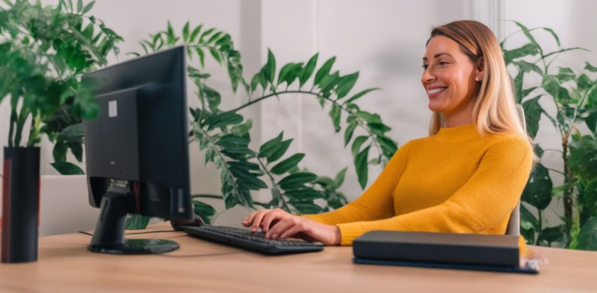 une femme devant son ordinateur travail avec le sourire
